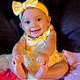 baby, child, smiling, yellow_clothing, headband, bow, sitting, blanket, happy, cute, indoors, infant, toddler, portrait, skin, feet, hand, face, person, bright
