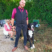 Volcano a rejoint le concours — aidez-le/la à gagner de superbes lots ! beard, boots, casual, chair, dog, elderly_woman, glasses, grass, great_dane, greenery, leash, man, outdoor, person, sitting, smile, sunlight, tie, tree, vest