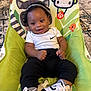 Carter is registered to the contest to win money with this photo: animal_print, baby, baby_chair, black_pants, carpet, child, clothing, colorful, cute, footwear, happy, headwear, indoor, infant, nike, person, sitting, smile, sneakers, white_shirt
