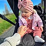 Joy participe au concours pour gagner de l'argent avec cette photo : baby, child, stroller, hand, pink_clothing, hat, bow, outdoor, sunny, daylight, grass, path, adult_hand, knitwear, cozy, cute, infant, person, holding, seated