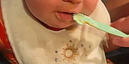 Nolan joined the competition — help win amazing prizes! baby, bib, child, close_up, clothing, colorful, cute, expression, face, feeding, food, hand, indoor, infant, mouth, nose, person, soft_toy, spoon, toy