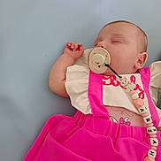 Ariah participe au concours pour gagner de l'argent avec cette photo : baby, sleeping, pacifier, pink_dress, infant, cute, child, rest, soft_background, close_up, clothing, person, peaceful, indoors, portrait, newborn, accessory, toddler, relaxation, sleep