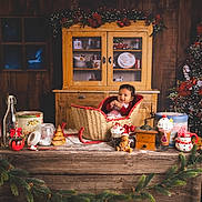 Kendrick a rejoint le concours — aidez-le/la à gagner de superbes lots ! baby, basket, christmas_tree, christmas_decorations, gingerbread_man, holiday, wooden_table, vintage_cabinet, cup, snowman_mug, candy_cane, whipped_cream, pine_garland, festive, smiling, indoor, child, holiday_spirit, cozy, red_clothing