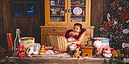 Kendrick a rejoint le concours — aidez-le/la à gagner de superbes lots ! baby, basket, candy_cane, child, christmas_decorations, christmas_tree, cozy, cup, festive, gingerbread_man, holiday, holiday_spirit, indoor, pine_garland, red_clothing, smiling, snowman_mug, vintage_cabinet, whipped_cream, wooden_table
