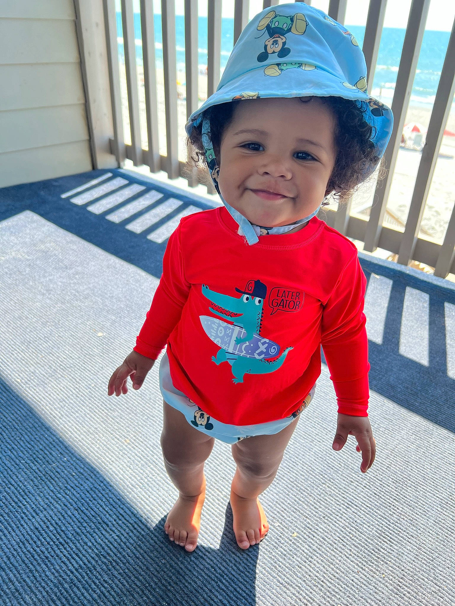 Isaiah is registered to the contest to win money with this photo: baby, baby_toddler_clothing, blue, child, electric_blue, fence, flooring, fun, happy, hat, headgear, headwear, human_leg, joy, leisure, pattern, person, play, sleeve, t_shirt