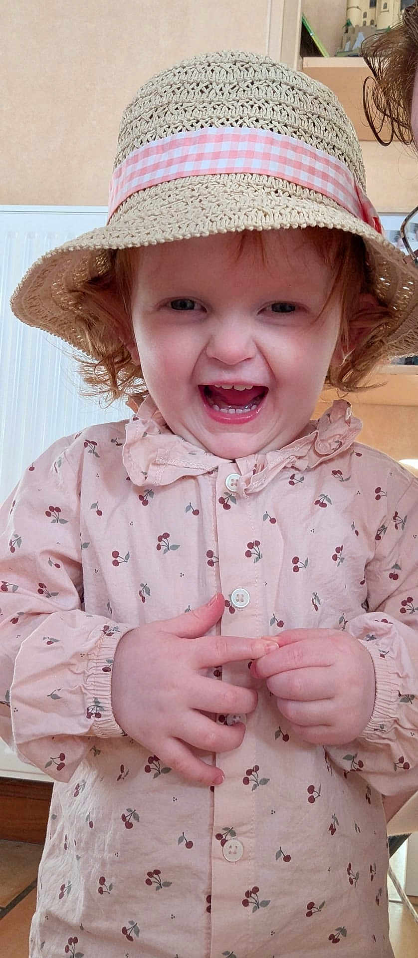 Ondine a rejoint le concours — aidez-le/la à gagner de superbes lots ! toddler, child, hat, straw_hat, pink_shirt, cherry_pattern, happy, laughing, indoor, curly_hair, face, person, cute, buttoned_shirt, young_child, smiling, clothing, portrait, hands, radiant