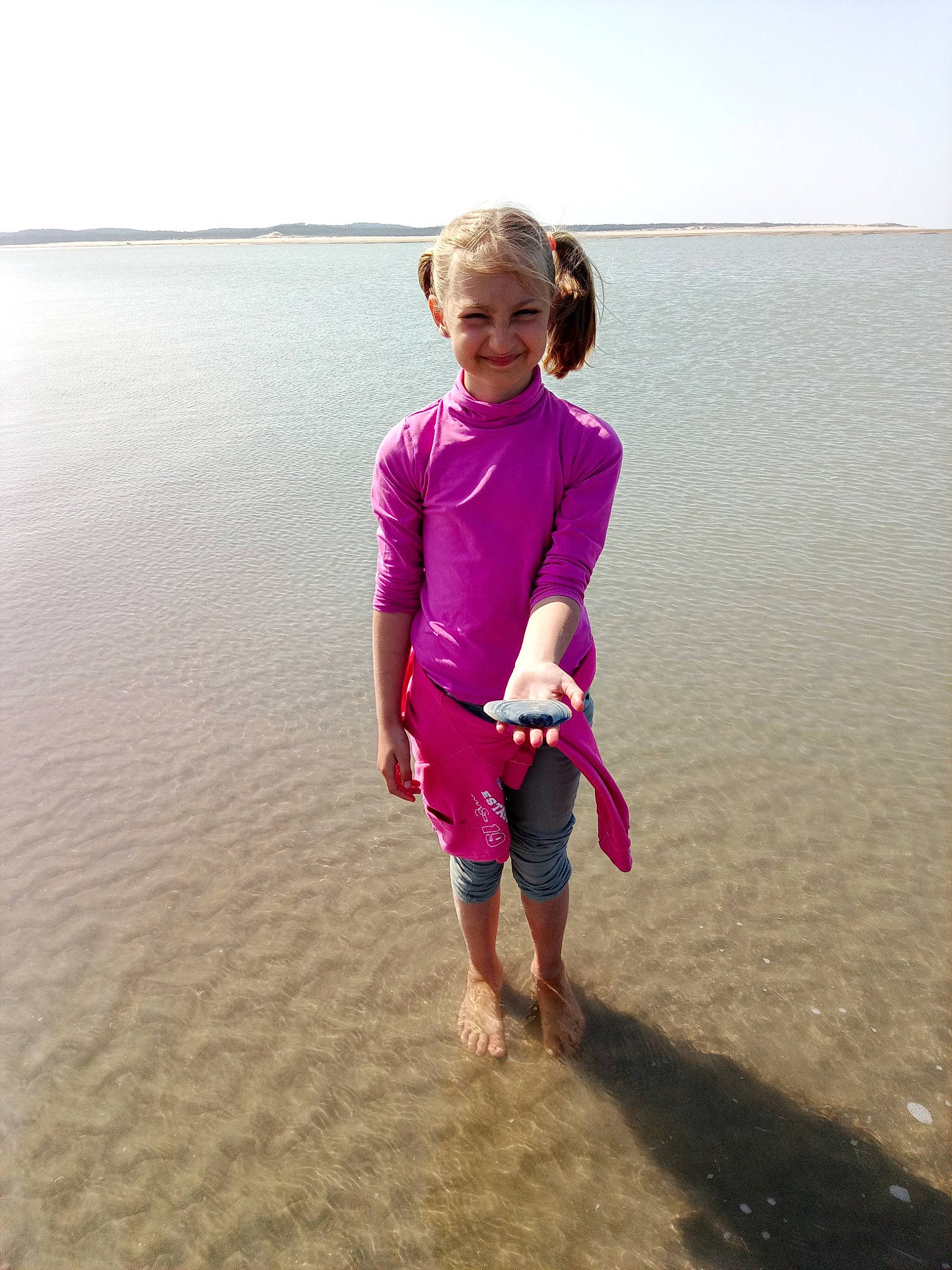 Gabrielle a rejoint le concours — aidez-le/la à gagner de superbes lots ! barefoot, beach, body_of_water, fun, gesture, happy, horizon, human_body, joy, magenta, people_in_nature, people_on_beach, person, shore, sky, sleeve, smile, standing, summer, toddler