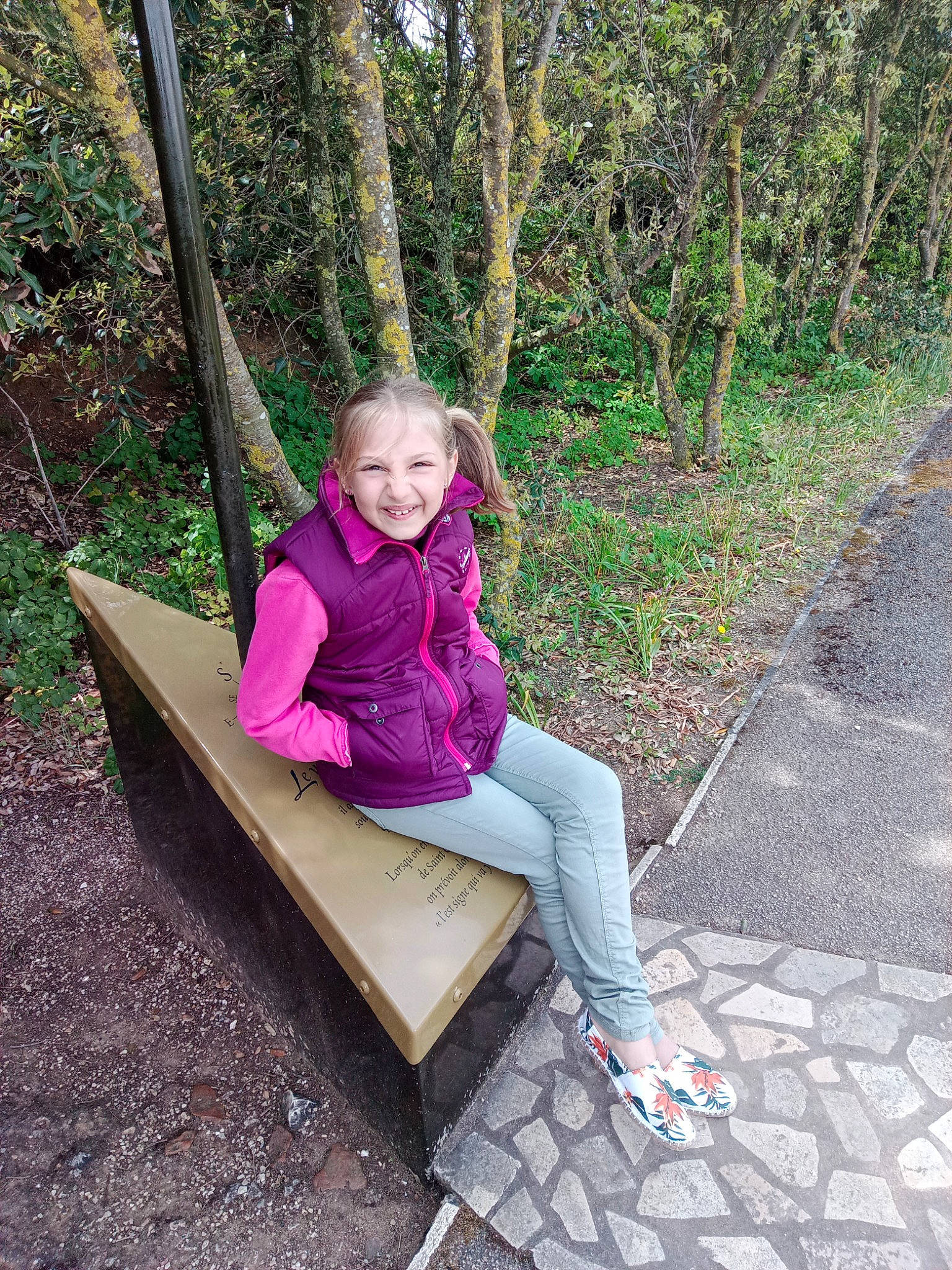 Gabrielle a rejoint le concours — aidez-le/la à gagner de superbes lots ! child, forest, fun, grass, happy, jacket, joy, leisure, magenta, outerwear, people_in_nature, person, plant, recreation, sandal, sitting, smile, spring, tree, wood