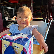 Hailey a rejoint le concours — aidez-le/la à gagner de superbes lots ! arm, baby, child, clothing, cute, face, furniture, hair, happy, high_chair, indoor, light, person, plush_toy, restaurant, seat, shadow, smile, table, toy