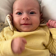 Lylah is registered to the contest to win money with this photo: baby, blanket, child, closeup, comfort, cute, face, hand, hood, indoors, infant, lying_down, person, portrait, ribbed_fabric, smile, soft_texture, striped_fabric, yellow_clothing, young