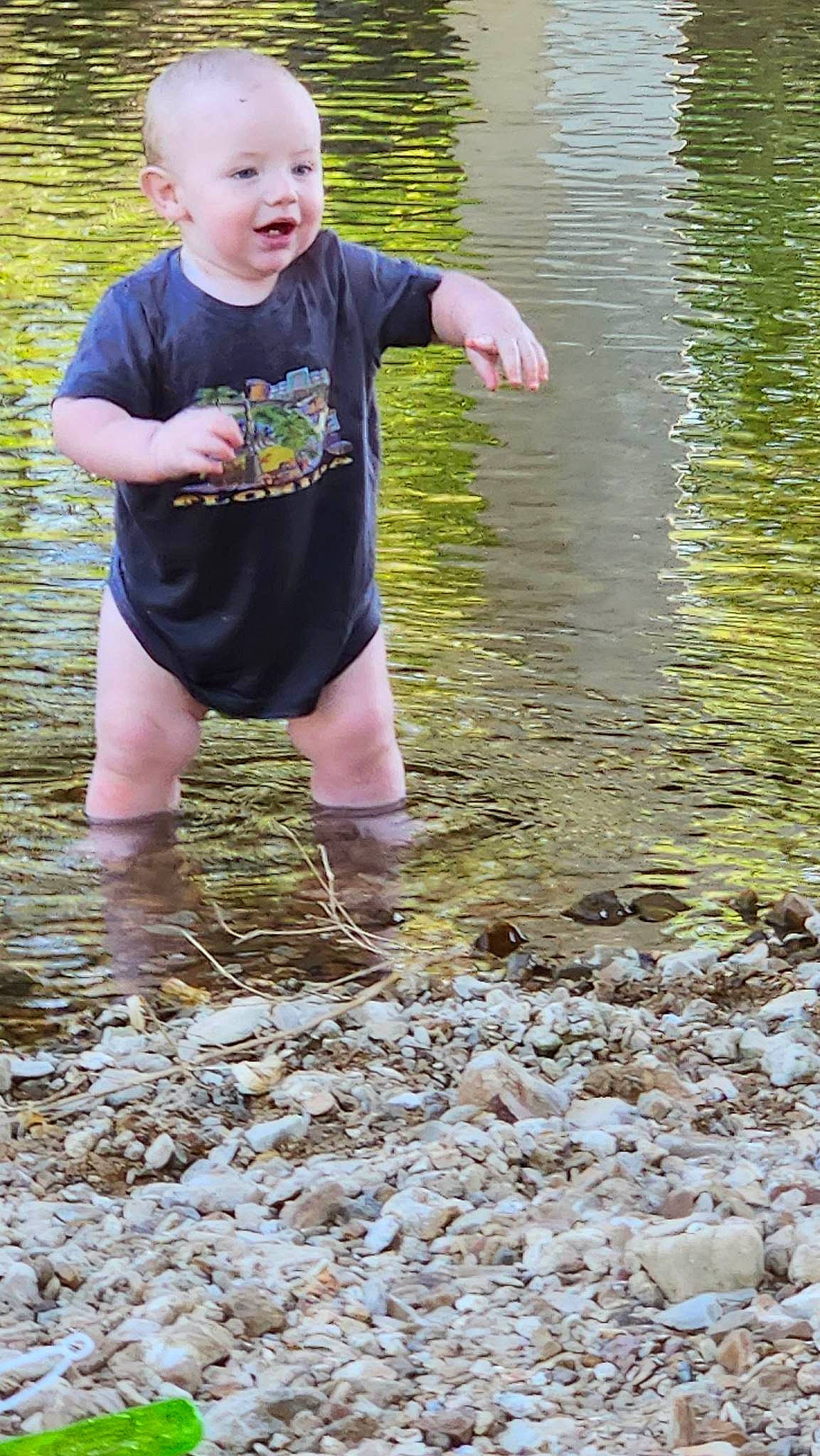 Deuteronomy is registered to the contest to win money with this photo: bank, fun, grass, hand, happy, lake, leisure, mud, people_in_nature, person, pond, recreation, reflection, shorts, smile, soil, stream, t_shirt, toddler, tree