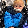 toddler, child, jacket, blue_jacket, stroller, bottle, indoor, face, curious, hand, clothing, person, young_child, seated, expression, baby, casual, warm_clothing, infant, portrait