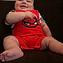baby, child, smiling, red_clothing, spiderman, couch, indoor, happy, infant, person, cute, sitting, plush, skin, feet, arms, legs, head, portrait, relaxed