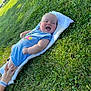 Carson is registered to the contest to win money with this photo: baby, grass, towel, blue_onesie, smiling, happy, outdoor, person, hand, infant, child, sunlight, nature, greenery, relaxing, cute, summer, playing, lying_down, cheerful