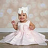 baby, child, toddler, portrait, smiling, dress, pink_dress, headband, bow, sitting, studio, indoors, fashion, baby_fashion, white, floor, backdrop, bokeh, watermark, text_overlay