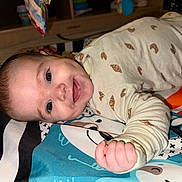 Emery joined the competition — help win amazing prizes! baby, smiling, lying_down, onesie, croissant_pattern, dimples, play_mat, colorful, indoor, child, happy, infant, face, cute, person, head, hand, furniture, soft_lighting, home
