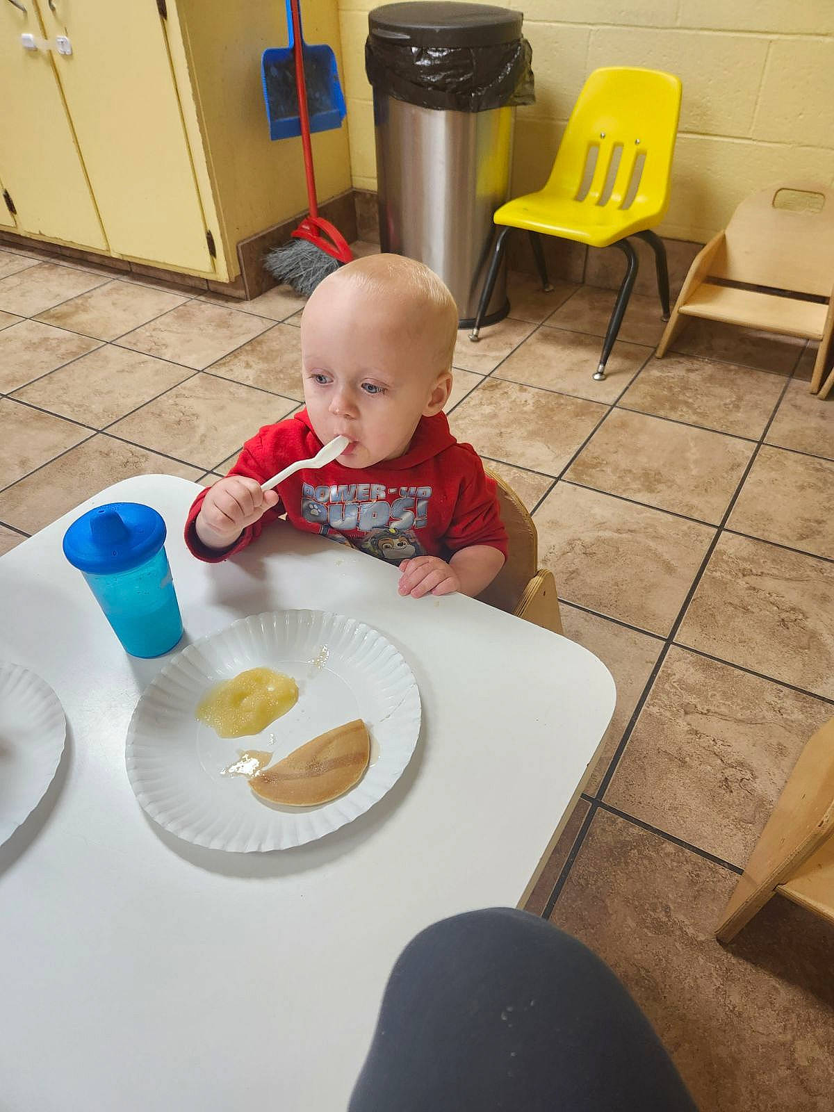 Jaxson is registered to the contest to win money with this photo: baby, chair, child, cooking, dishware, floor, flooring, food, hardwood, person, plate, room, serveware, sitting, t_shirt, table, tableware, toddler, waste_container, wood