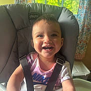 Leilany joined the competition — help win amazing prizes! baby, smiling, high_chair, child, face, happy, indoors, shirt, clothing, window, curtains, seat_belt, person, young_child, toy, hand, head, expression, home, light
