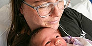 Leilany joined the competition — help win amazing prizes! newborn, baby, adult, glasses, hospital_bed, blanket, portrait, closeup, face, skin, person, holding, caring, indoor, comfort, family, love, mother, child, rest