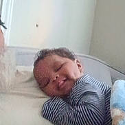 Kyro is registered to the contest to win money with this photo: baby, bed, bedding, bedroom, blanket, child, closed_eyes, cozy, curled_up, indoors, infant, lying_down, nap, pajamas, peaceful, portrait, resting, sleeping, soft_lighting, striped_clothing