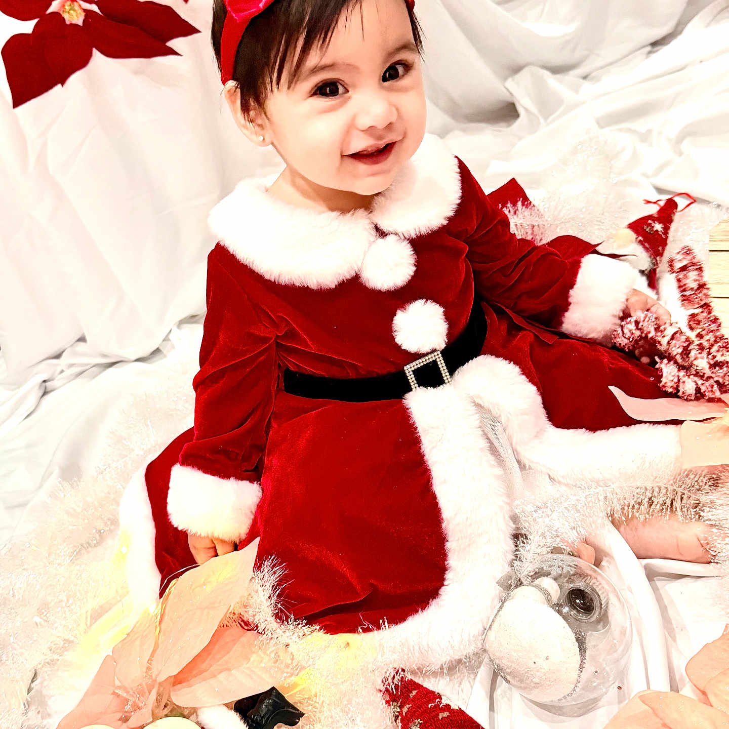 Dannha joined the competition — help win amazing prizes! baby, bow, child, christmas, decorations, festive, fur_trim, gnome, holiday, indoor, plush_toy, poinsettia, portrait, red_dress, red_headband, santa_costume, sitting, smiling, toddler, white_background