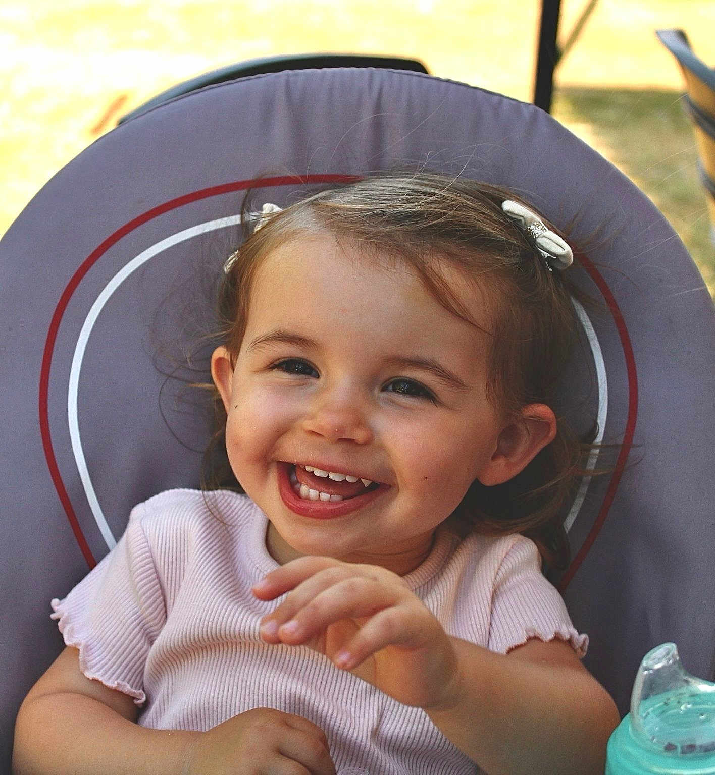 Albane participe au concours pour gagner de l'argent avec cette photo : toddler, child, smiling, happy, baby_bottle, chair, hair_clip, outdoor, daylight, clothing, person, face, cute, young_child, sitting, playful, joyful, skin, hand, casual