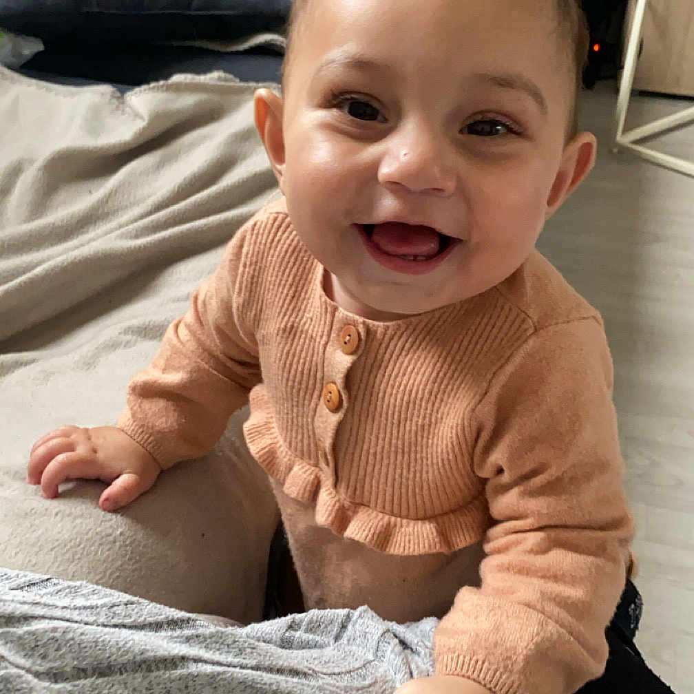 Lenaya participe au concours pour gagner de l'argent avec cette photo : baby, bed, bodypart, clothing, couch, cushion, face, finger, furniture, hand, happy, head, homedecor, indoors, pants, person, photography, portrait, sitting, smile