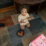 Amiyah is registered to the contest to win money with this photo: toddler, child, pizza, food, kneeling, rug, carpet, table, indoor, messy, hair, shirt, pink_suitcase, stickers, floor, wooden_table, looking_up, casual_clothing, home, meal
