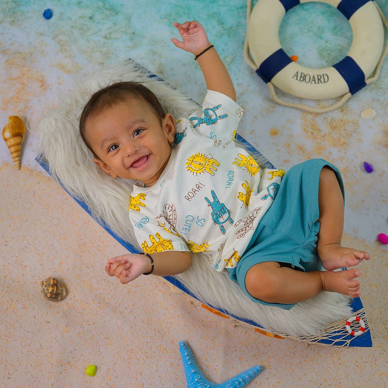 Kaveer joined the competition — help win amazing prizes! baby, beach, blue_shorts, boat, child, colorful_decor, cushion, cute, fabric, floor, happy, indoor, playful, portrait, raising_hand, shells, smiling, starfish, toy, white_tshirt