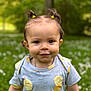 Gëovanna a rejoint le concours — aidez-le/la à gagner de superbes lots ! toddler, child, smiling, outdoor, greenery, grass, flowers, hair_ties, blue_shirt, fruit_pattern, young_child, cute, portrait, nature, happy, person, sunlight, casual_clothing, daylight, baby