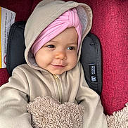 Gëovanna participe au concours pour gagner de l'argent avec cette photo : apparel, baby, blanket, car_seat, child, cozy, cute, expression, fabric, face, fuzzy_blanket, headwear, hoodie, indoor, infant, pink_headwrap, portrait, seat, smile, warm_clothing