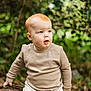 Jax is registered to the contest to win money with this photo: toddler, child, red_hair, outdoor, forest, log, nature, curious, blue_eyes, casual_clothing, beige, cream, long_sleeve, pants, sitting, young_child, portrait, daylight, greenery, exploration