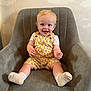 Bailey is registered to the contest to win money with this photo: toddler, child, smiling, yellow_overalls, white_socks, blond_hair, blue_eyes, grey_chair, indoor, portrait, happy, baby, cute, sitting, furniture, wallpaper, clouds, casual_clothing, human, home