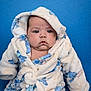 baby, child, infant, hooded_robe, fluffy_clothing, blue_background, cute, chubby_cheeks, portrait, sitting, serious_expression, soft_texture, warm_clothing, indoor, person, young_child, closeup, skin, face, head