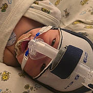 Layla is registered to the contest to win money with this photo: baby, bed, blanket, breathing_mask, cap, care, child, closeup, eyes, face, healthcare, hospital, infant, lying_down, medical_equipment, medical_mask, newborn, patient, pattern, soft_lighting