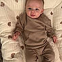 baby, infant, pajamas, quilt, blanket, teddy_bear_pattern, smiling, tongue_out, lying_down, soft_texture, cute, child, indoors, cozy, comfort, face, hands, legs, happy, playful