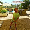 Petru a rejoint le concours — aidez-le/la à gagner de superbes lots ! child, boy, smiling, outdoor, sunlight, patio, umbrella, chair, greenery, trees, shorts, tshirt, sandals, happy, playful, daytime, person, summer, shadow, recreation