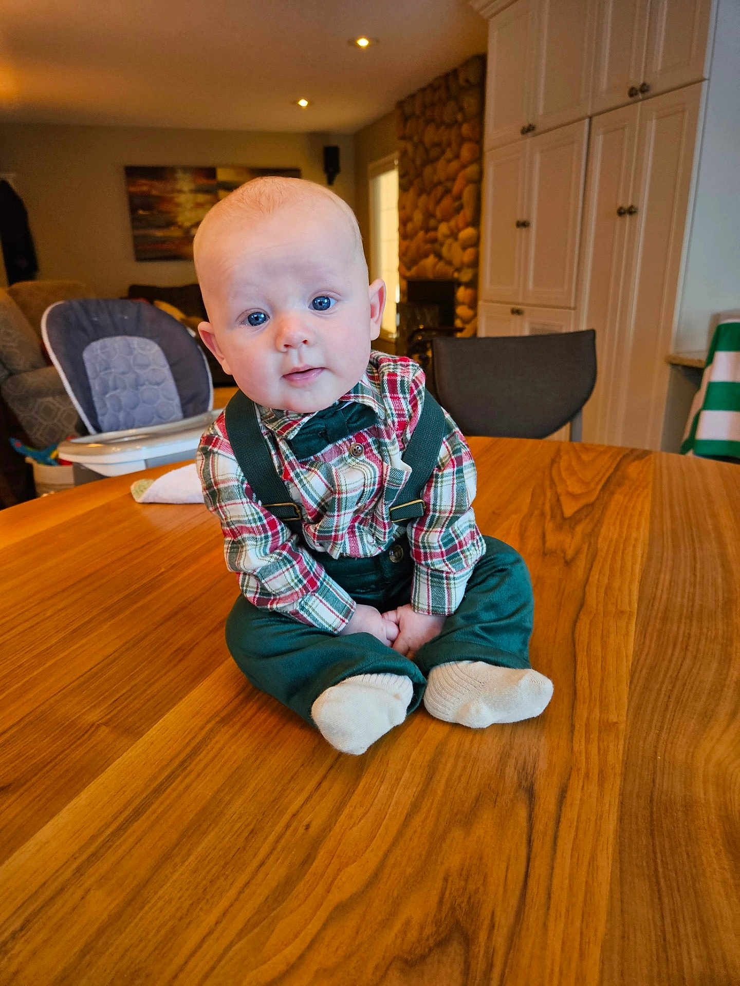 Stetson joined the competition — help win amazing prizes! baby, child, plaid_shirt, suspenders, bow_tie, table, wood, indoor, living_room, chair, high_chair, couch, window, cabinet, stone_wall, person, cute, portrait, sitting, curious