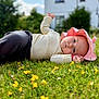 baby, child, cute, daylight, flora, grass, greenery, headwear, infant, lawn, lying_down, nature, outdoor, person, pink_hat, portrait, relaxing, sweater, yellow_flowers, young_child