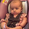 Anora is registered to the contest to win money with this photo: baby, infant, car_seat, child, seatbelt, harness, pink, clothing, face, head, skin, foot, hand, expression, sitting, indoor, text_warning, fabric, closeup, person