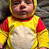 baby, child, costume, yellow, bear, hood, ears, blanket, cute, infant, clothing, red_sleeves, face, portrait, person, indoors, soft_texture, lying_down, expression, warm