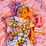 adorable, baby, baby_face, celebration, child, clothing, cookie, cute, headband, infant, lying_down, month_sign, newborn, number_one, one_month_old, pink_blanket, plaid_outfit, portrait, small_hands, soft_texture