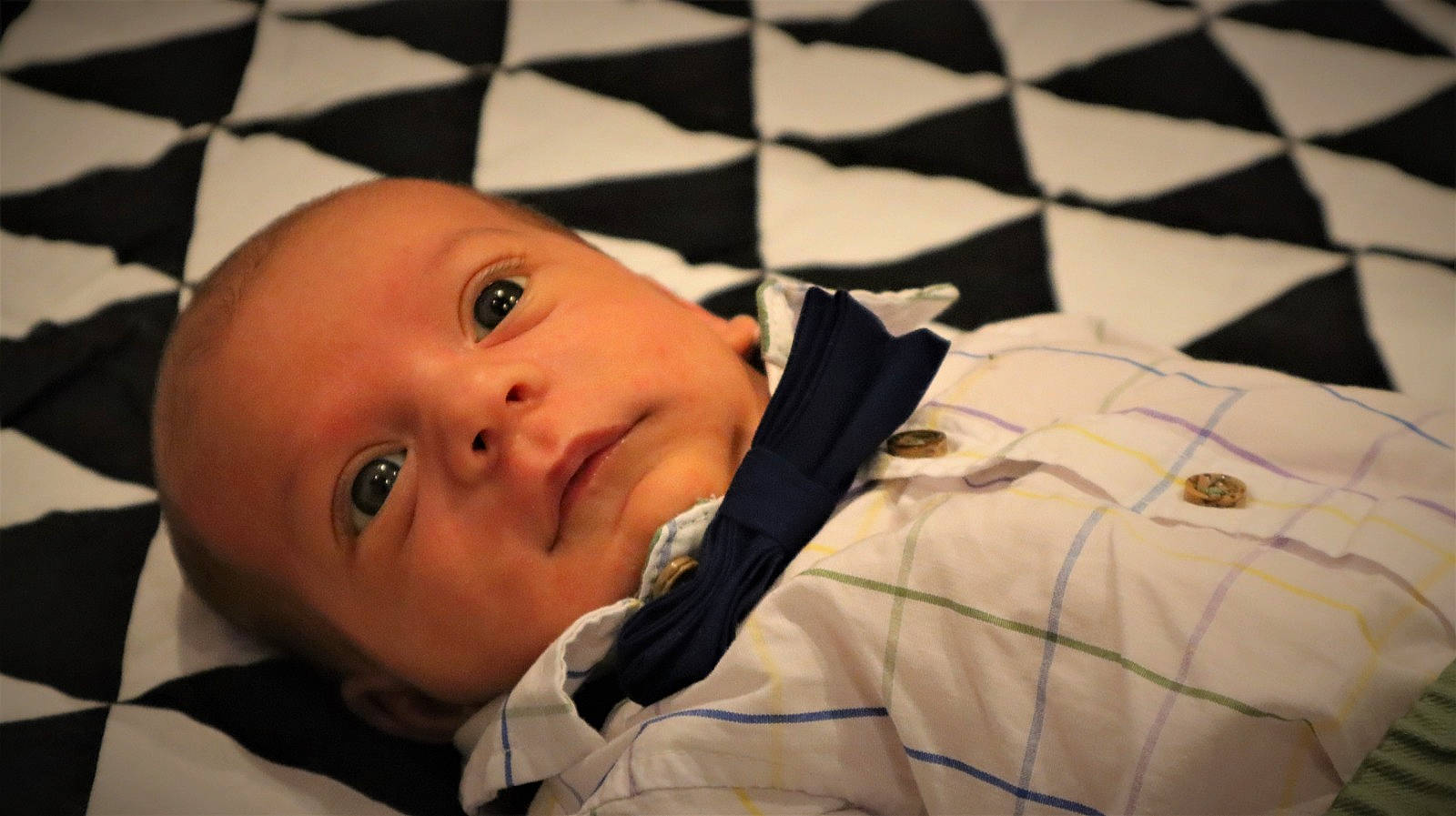 Evan is registered to the contest to win money with this photo: baby, baby_products, black, cheek, child, comfort, eyelash, flooring, fun, linens, mouth, nose, pattern, person, room, square, toddler