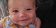 Emari is registered to the contest to win money with this photo: baby, smiling, dimples, shirt, pattern, cartoon, sandwich, clothing, face, infant, person, cute, portrait, indoors, cushion, comfort, young_child, happy, closeup, skin