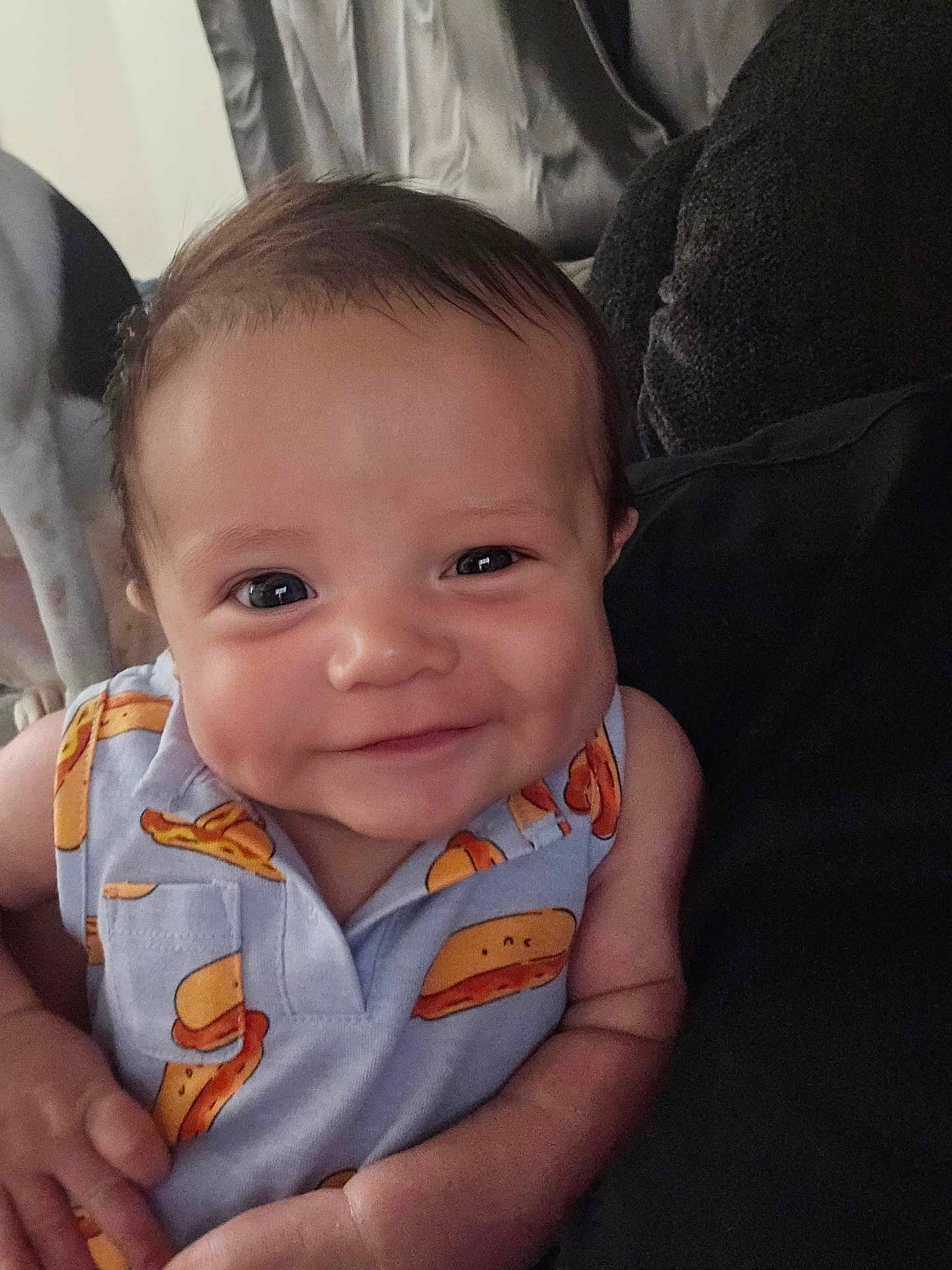 Emari is registered to the contest to win money with this photo: baby, smiling, dimples, shirt, pattern, cartoon, sandwich, clothing, face, infant, person, cute, portrait, indoors, cushion, comfort, young_child, happy, closeup, skin