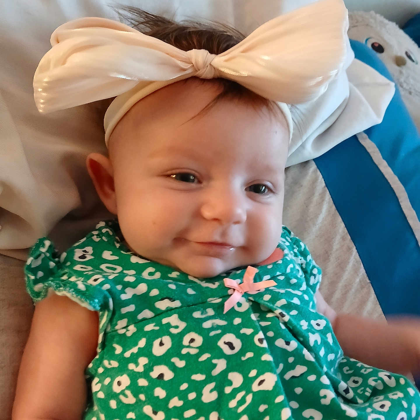 Brenleigh joined the competition — help win amazing prizes! baby, bed, bow, child, cozy, cushion, cute, face, green_dress, happy, headband, indoors, infant, patterned_clothing, person, portrait, resting, smile, soft_lighting, young_child