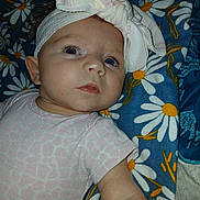 Brenleigh joined the competition — help win amazing prizes! baby, infant, headband, bow, blanket, daisy_pattern, pink_clothing, blue_background, child, face, skin, cute, lying_down, soft_fabric, portrait, small_person, young_child, indoor, closeup, expression