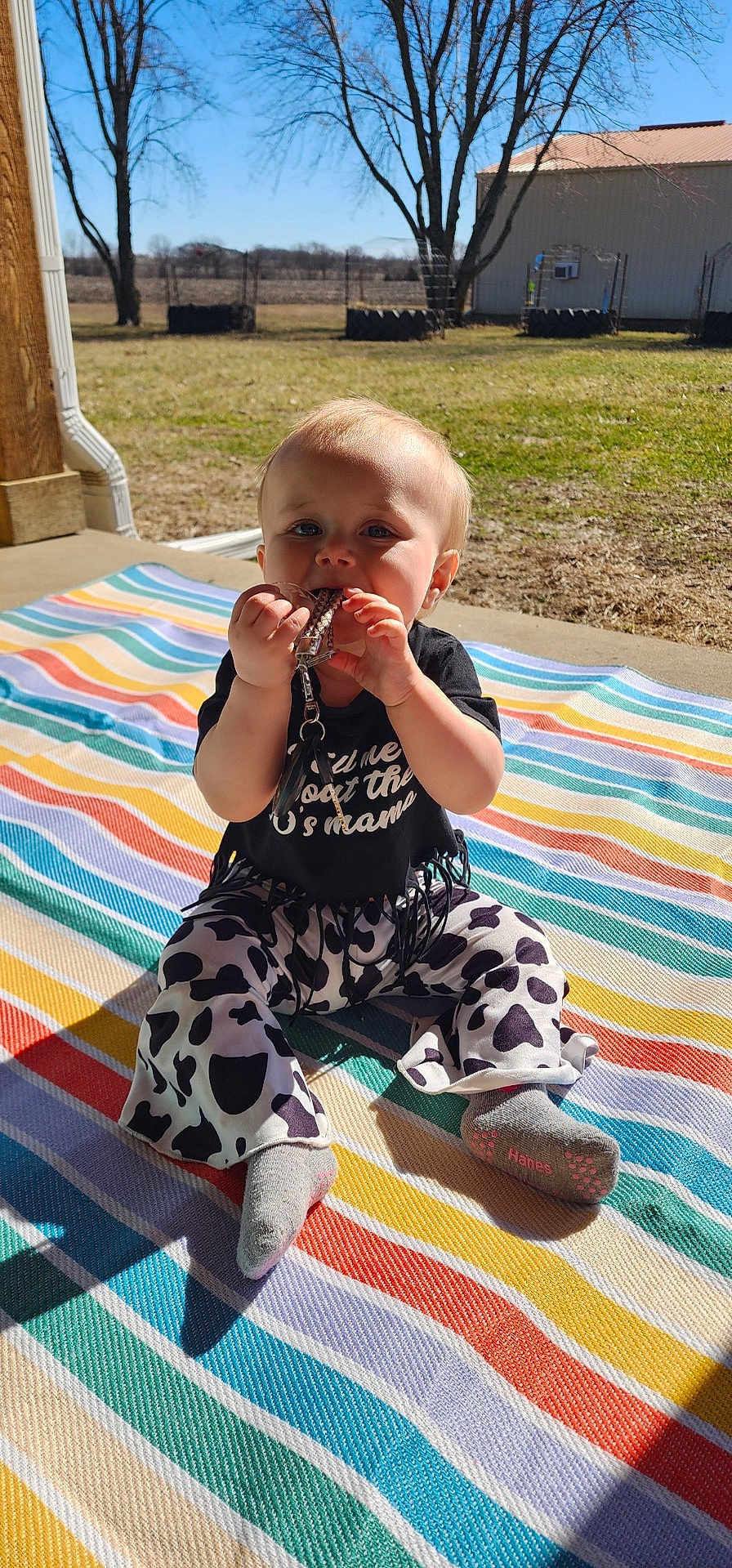 Patsy joined the competition — help win amazing prizes! baby, infant, child, toddler, sitting, striped_blanket, keys, keychain, chewing, socks, patterned_pants, porch, sunlight, outdoor, grass, trees, building, smile, face, shadow