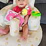 Patsy is registered to the contest to win money with this photo: baby, infant, cushion, teddy_bear_print, toy, pink_clothing, yellow_plush_toy, green_toy, sofa, blanket, happy, face, smiling, indoor, child, seated, comfort, playtime, cute, blue_eyes