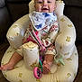 baby, infant, child, inflatable_chair, teddy_bear_pattern, bib, floral_outfit, toy, soft_book, pink_toy, purple_toy, smiling, indoor, wood_floor, cute, seated, barefoot, happy, person, portrait